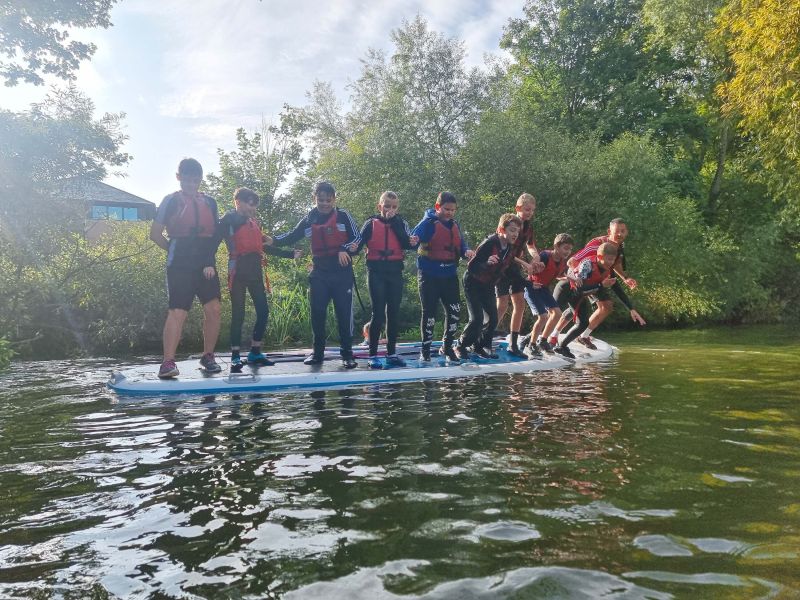 Kids standing up on a standing up paddle board at childrens party