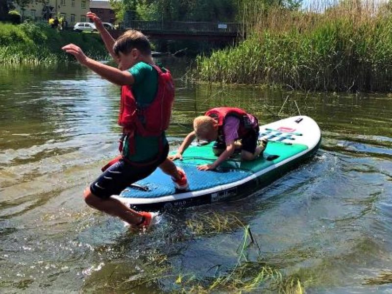 Kids jumping into water from paddleboard