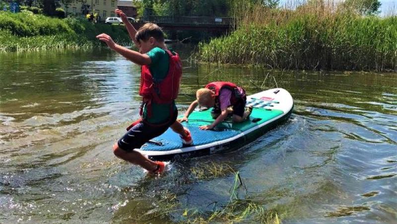 Kids jumping into water from paddleboard