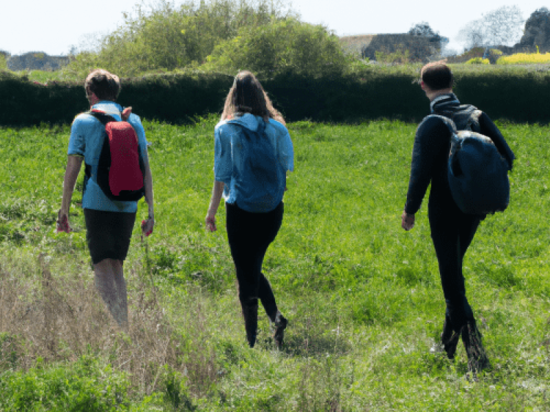 Students walking through a field on a school walking on a navigation and map reading trip